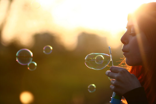 Netherlands, Amsterdam, Side view of young woman blowing bubbles