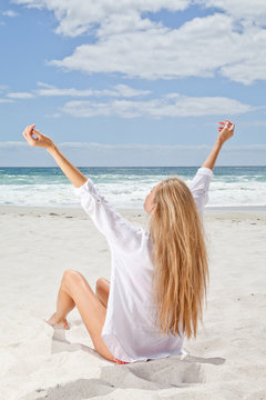 Young woman on beach with outstretched arms