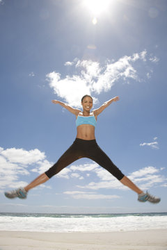 Smiling woman jumping mid air on the beach, Cape Town, Western Cape, South Africa