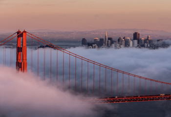 Golden gate bridge through the fog with city skyline in the distance, San Francisco, California, USA