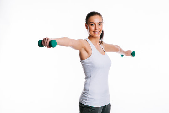 Smiling young woman in sportswear with her arms outstretched doing dumbbell lateral raises
