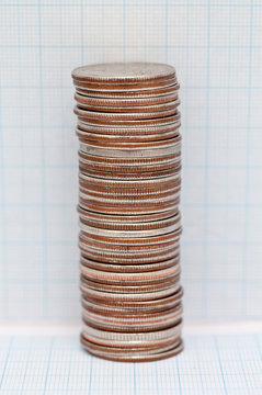 Close-up of a large Stack of quarters in front of graph paper