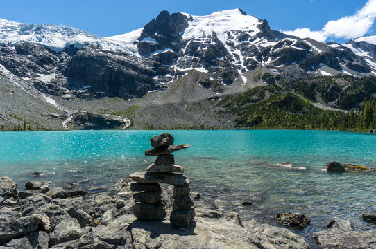 Traditional stone Inukshuk navigation marker on the rocky shoreline of Upper Joffre Lake, Joffre Lakes Provincial Park, British Columbia, Canada