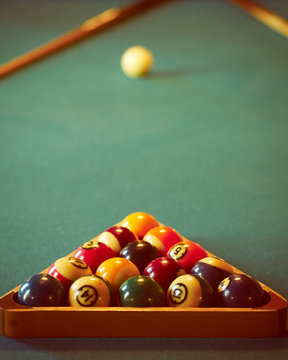 Close-up shot of pool balls in wooden triangle with cue ball in blurred background