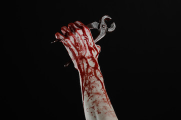 bloody hand holding a pliers on a black background