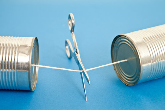 Close-up of a pair of Scissors cutting the string of a Tin Can phone