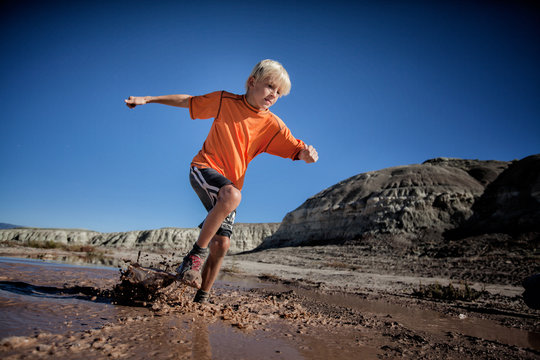 USA, Colorado, Boy (6-7) trail running through wet mud