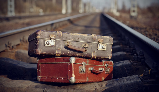 The image of two vintage suitcases on railway tracks.