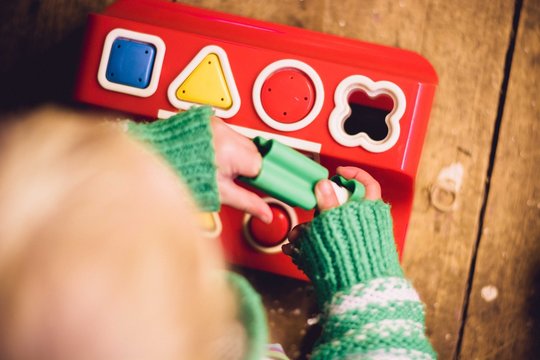 Overhead view of baby girl (2-3) playing with shape board