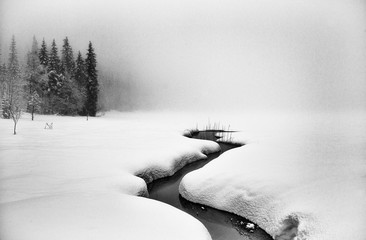 Stream flowing through a rural snowy winter landscape, Trantjern, Jevnaker, Oppland, Norway