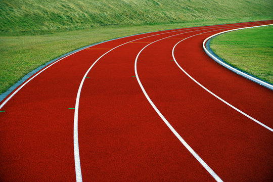 Close-up of a curved running track bordered by green grass, finland