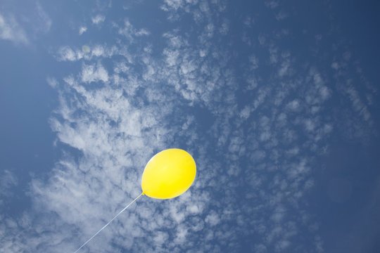 Single Yellow Balloon Against Blue Sky