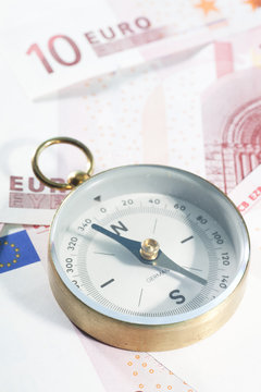 Full frame close-up of a metal compass on assorted Euro banknotes