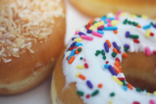 Full frame close-up of three donuts with icing, sprinkles and shredded coconut