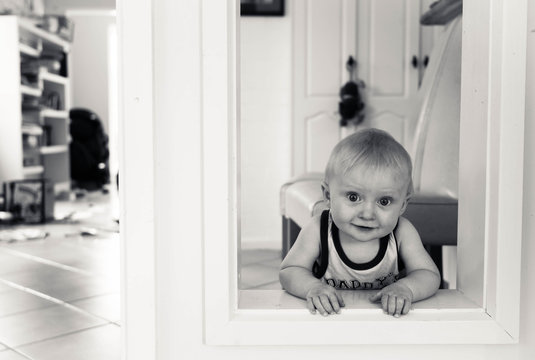 Australia, Canberra, Hackett, Baby boy (6-11 months) playing peekaboo around door frame