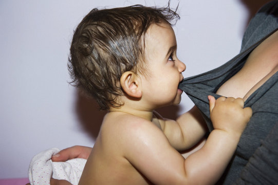 Baby boy biting on mother's shirt