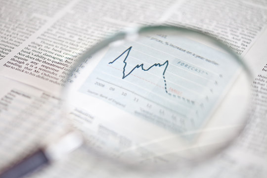 Close-up of a magnifying glass focused on a financial market graph in a document