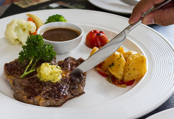 man's hand cutting on rib eye steak