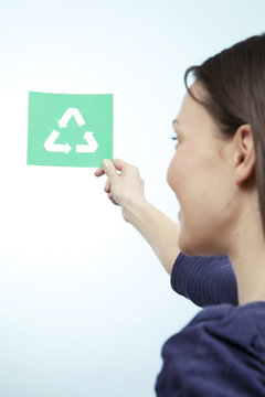 Woman holding paper cut out of the universal recycling symbol