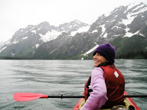 USA, Alaska, Young woman kayaking near glaciers in Kenai Fjords National park