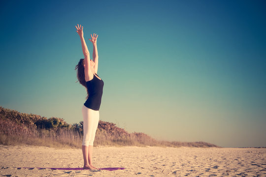 Woman practicing yoga on beach 
