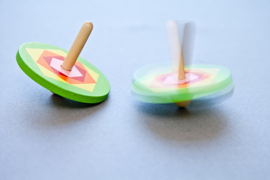 Close-up of two wooden Spinning Tops spinning on a table
