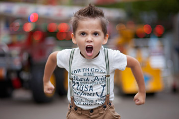 Portrait of an angry boy  standing in the street flexing his muscles and shouting