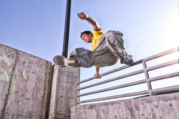 USA, Colorado, Mesa County, Grand Junction, Man making parkour jump on urban roof top