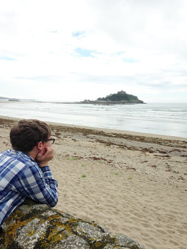 United Kingdom, Cornwall, Marazion, Boy lying on rock and looking at view