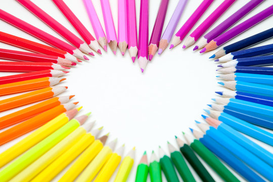 Overhead close-up view of coloured Pencils arranged on a table to form a heart shape