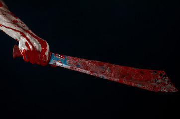 bloody hands holding a bloody machete isolated in studio