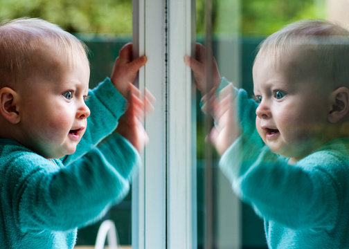 Australia, Canberra, Hackett, Baby boy (6-11 months) playing with his reflection in window