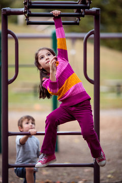 Girl and boy playing on climbing frame in a playground