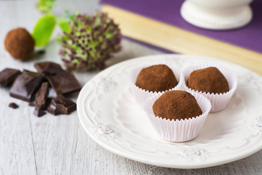 Close-up of Three homemade dark chocolate truffles dusted with cocoa powder and pieces of chocolate on a table