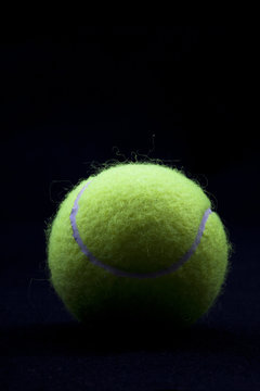 Close up of a tennis ball in front of a black background