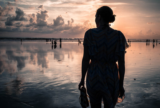 Indonesia, Bali, Legian, Silhouette of woman on beach at sunset