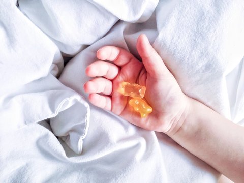 Toddler holding teddy bear wine gums