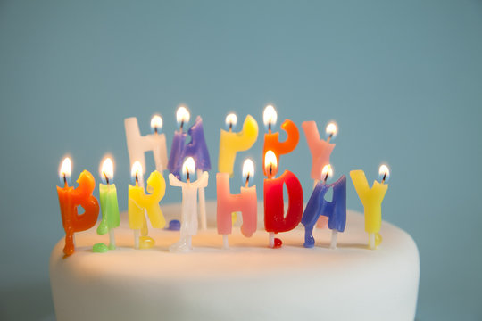 Lit Happy Birthday candles on a birthday cake