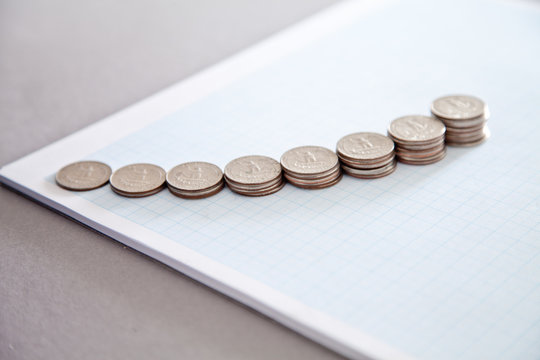 Close-up of ascending stacks of US quarters on graph paper