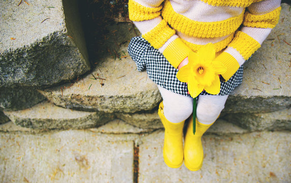 Overhead view of a young girl sitting on a step holding a daffodil