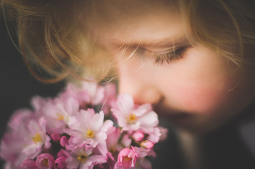 Extreme close-up of a young boy smelling a bunch of pink flowers