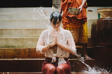Close up of monk giving water blessing to young woman