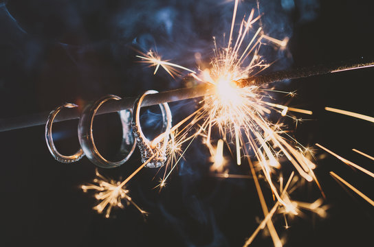 Wedding Rings hang on a sparkler as it burns down illuminating the rings