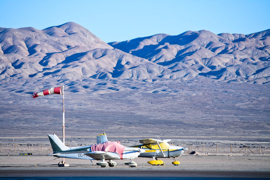 Chile, Atacama Desert, Two small airplanes at airport, mountains in background
