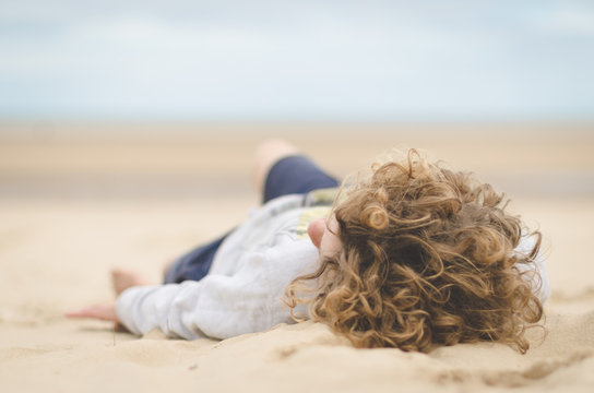 UK, England, Norfolk, Holkam, Boy (14-15) lying on beach