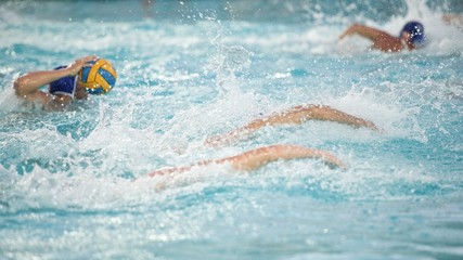 Four people playing water polo in a swimming pool