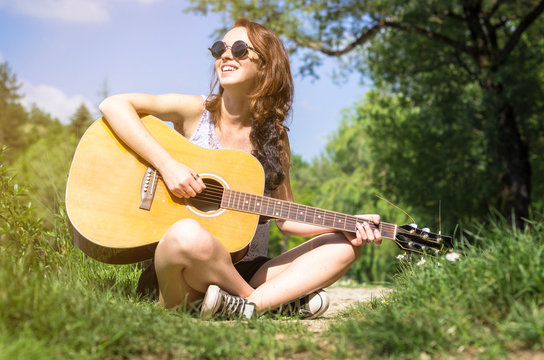 Girl is playing his guitar in a park - lifestyle concept