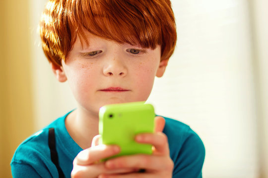 Young boy (4-5) playing mobile game on his mother's phone