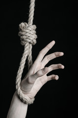 Fototapeta na wymiar human hand hanging on rope loop on a black background