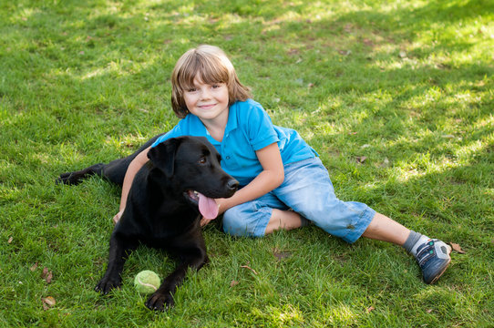 Boy (6-7) lying on lawn with dog